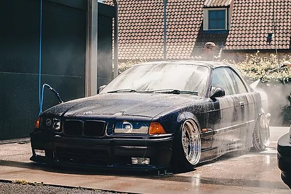 Dark coupe being washed — water mist over the paint